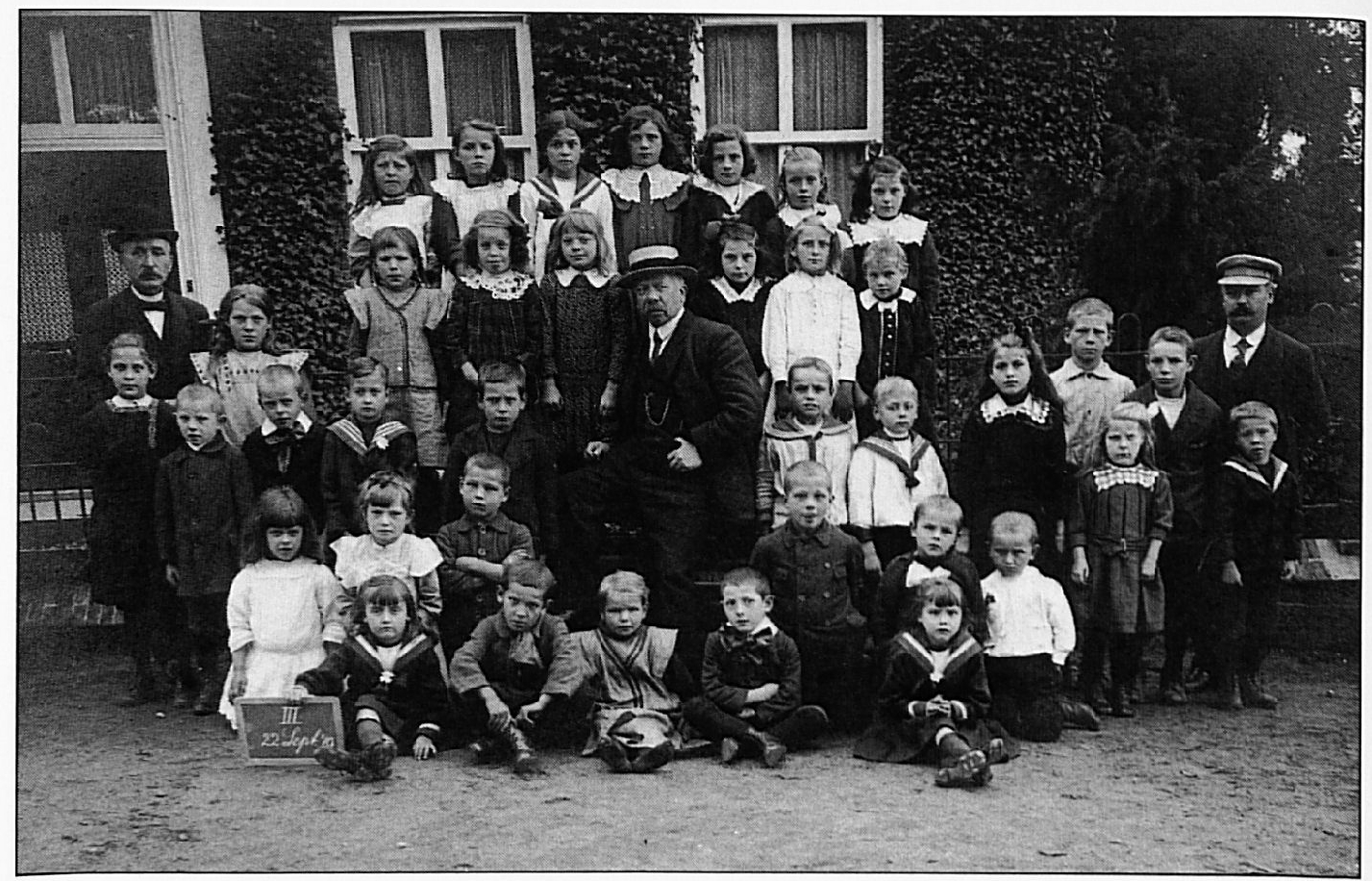 Deze derde schoolfoto van 22 sept. 1919 toont op de achterste rij v.l.n.r.: Anna Laponder, Jaan Peters, Filomeen Maas, Marie Melis, Riek Melis, Gon van Lent, Toos Nijs. Tweede rij van achteren: Meester Vincent, ..... , ..... , Anneke van Lent, Truus Melis(?), Grada Nijs, ..... , ..... Derde rij van achteren: ..... , Thé Melis, Johan van Lent, Harry Maas, .. ... , Meester Otten, Adri Peters, Jo Meijer, Nel Peters, Johan Melis, Cees Peters. Meester Van Oijen, ervoor staan Nellie Peters en Albert van Oijen. Vierde rij van achteren: ..... , ..... , Johan(?) van Kessel, Harry \1elis, Chris Peters, Ernst van Oort(?). Voorste rij: Cato Visser, Toon van Lith, ..... , Marinus Nijs, Riek Visser.